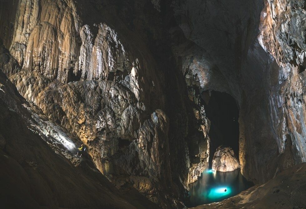 Grande grotte ornée de concrétions, avec un lac souterrain turquoise