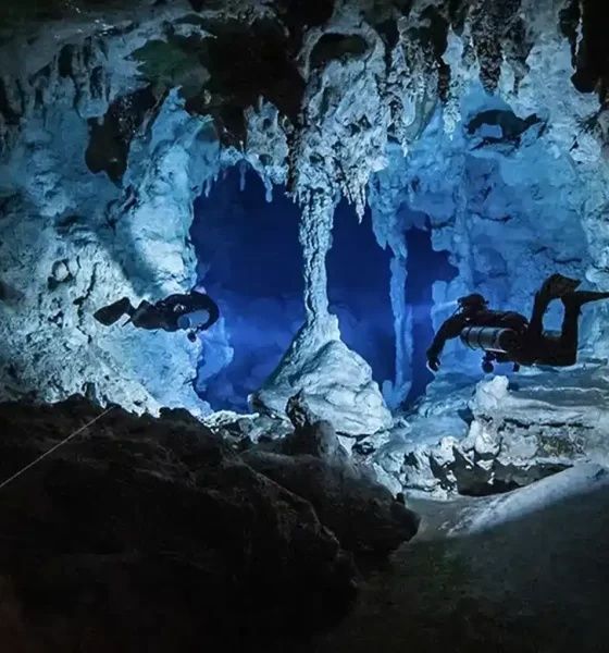 Deux plongeurs explorent une grotte sous-marine éclairée en bleu