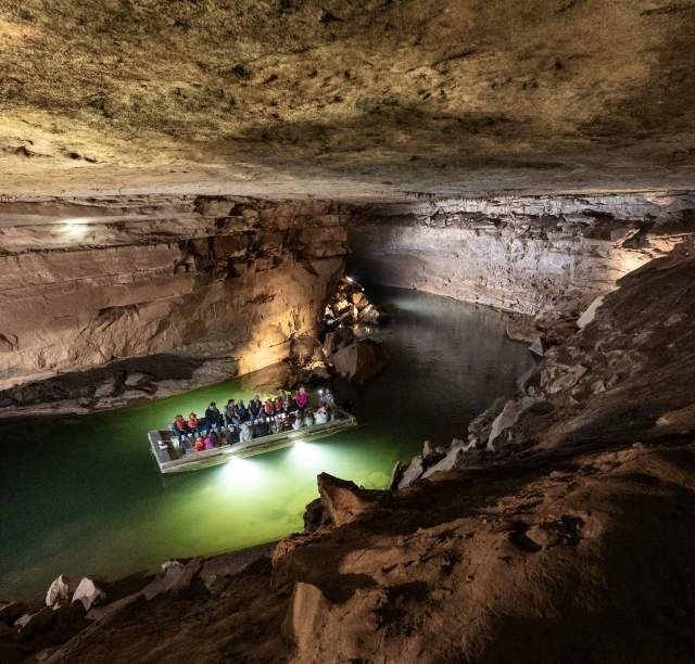 Bateau transportant des visiteurs sur une rivière souterraine éclairée