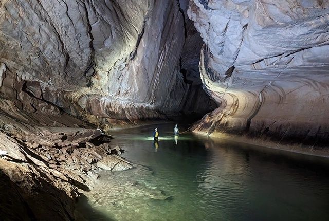 Deux personnes dans l’eau d’une vaste grotte karstique