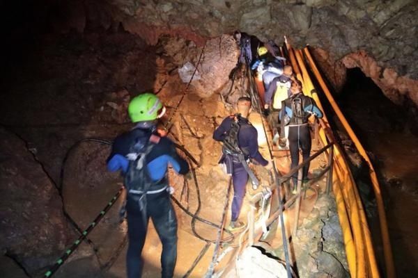 Spéléologues équipés progressant dans une cavité rocheuse avec des cordes